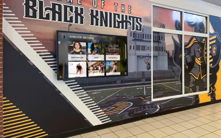 An athletic records touchscreen set into a hallway mural